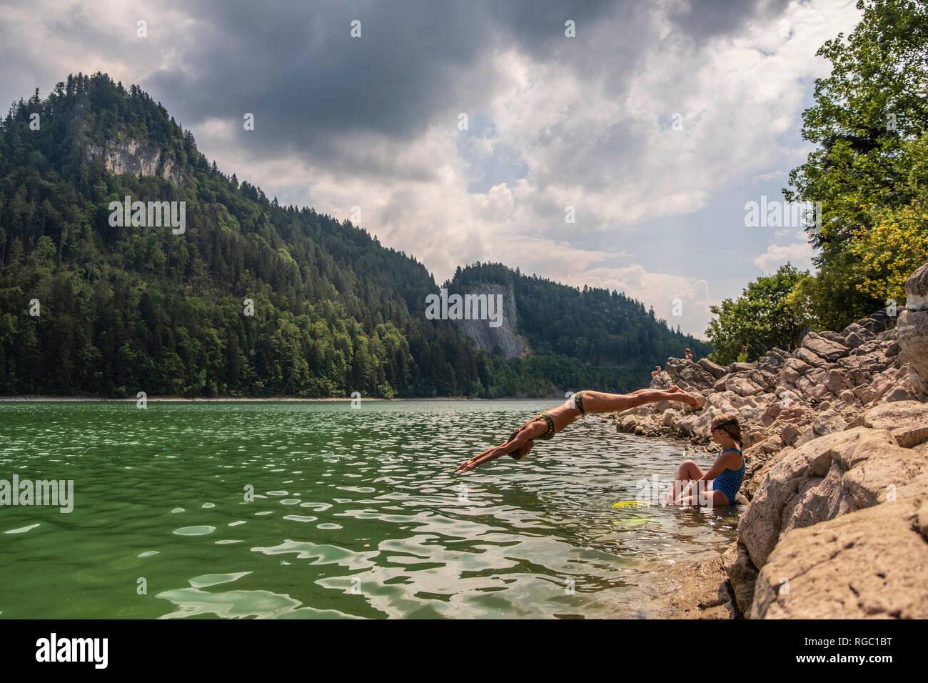 Austria, Salzkammergut, Mondsee, donna con figlia saltando nel lago Foto Stock
