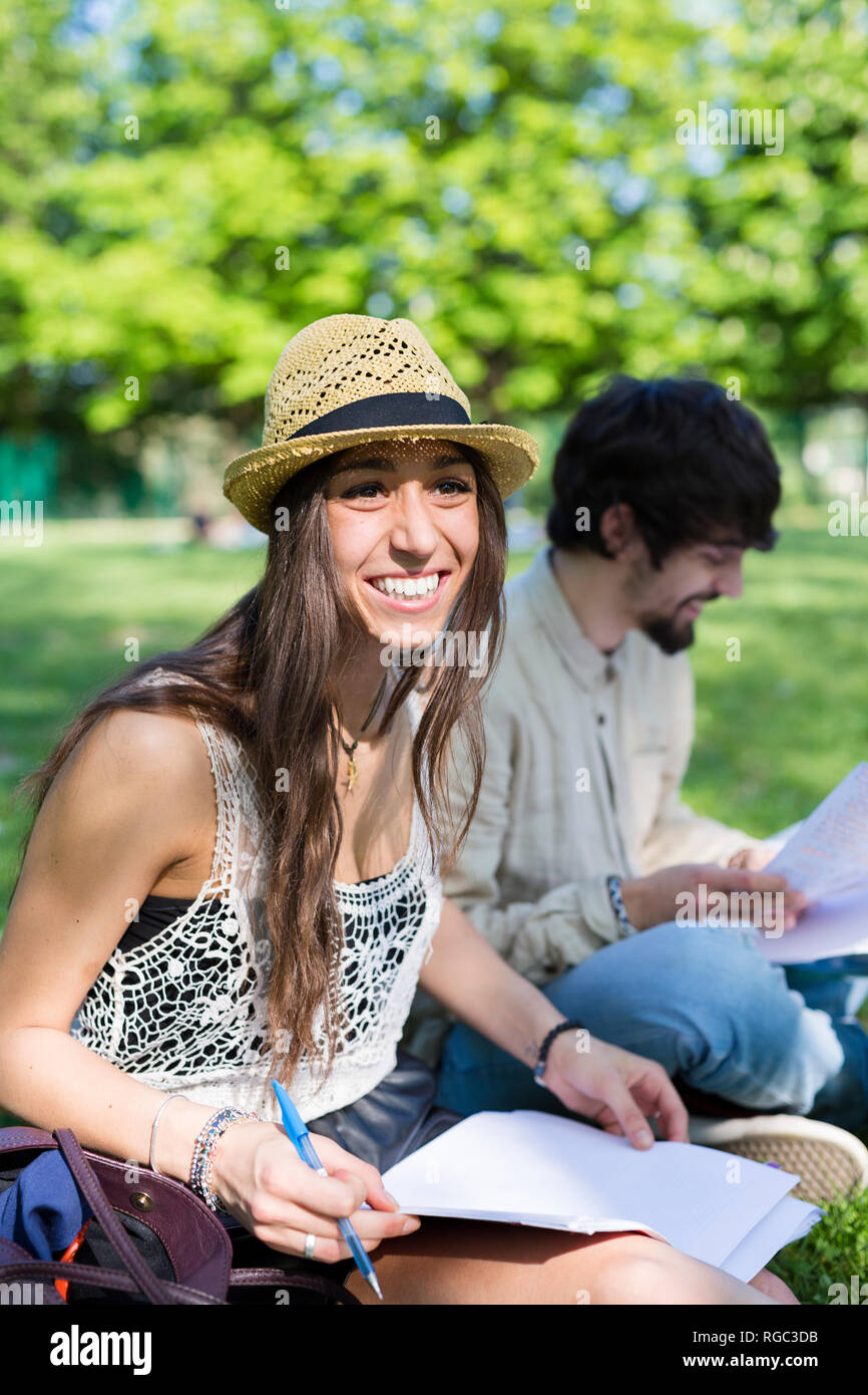 Ritratto di felice giovane studente seduto nel parco Foto Stock