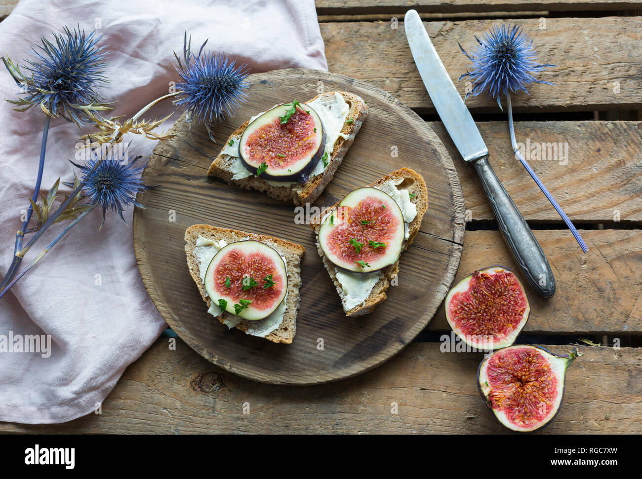 Fette di pane imburrate con spicchi di fichi sul piatto di legno Foto Stock