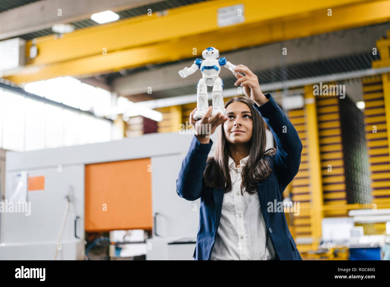 Giovane donna che lavorano nel magazzino di distribuzione, guardando il robot giocattolo Foto Stock