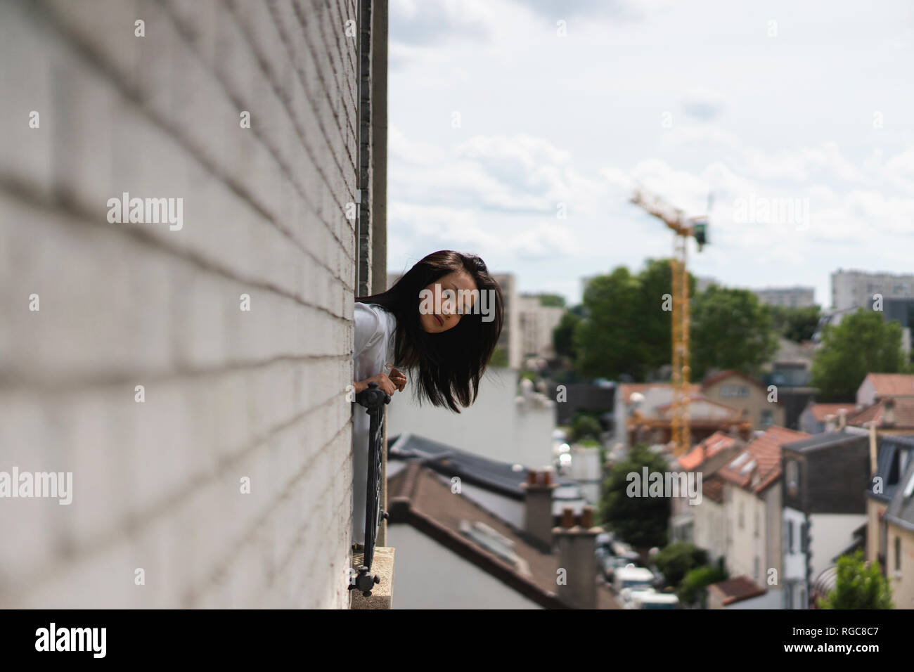 Francia, Parigi, giovane donna guardando fuori della finestra Foto Stock