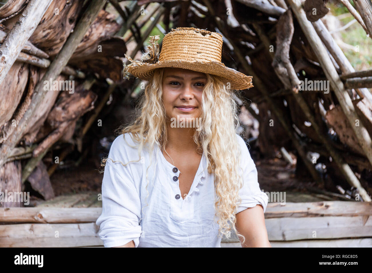 Ritratto di giovane sorridente donna che indossa cappello di paglia al rifugio in legno Foto Stock