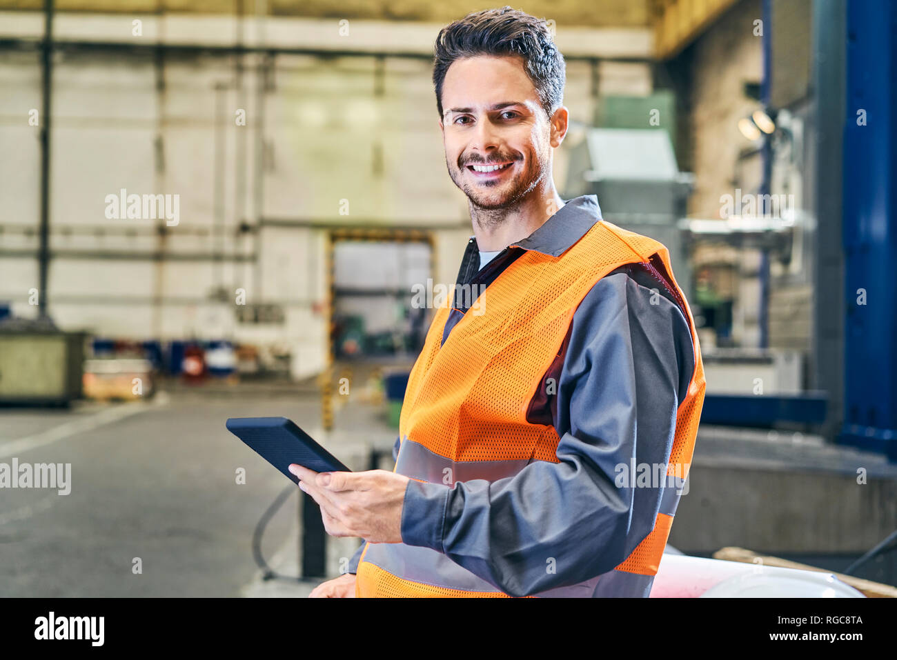 Ritratto di uomo sorridente holding tablet in fabbrica Foto Stock