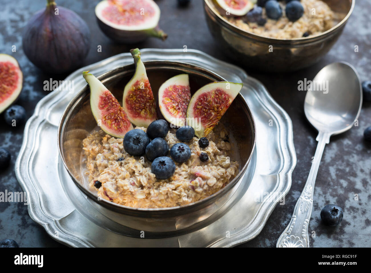 Ciotola di porridge con fette di fig, mirtilli e frutti di bosco essiccati Foto Stock