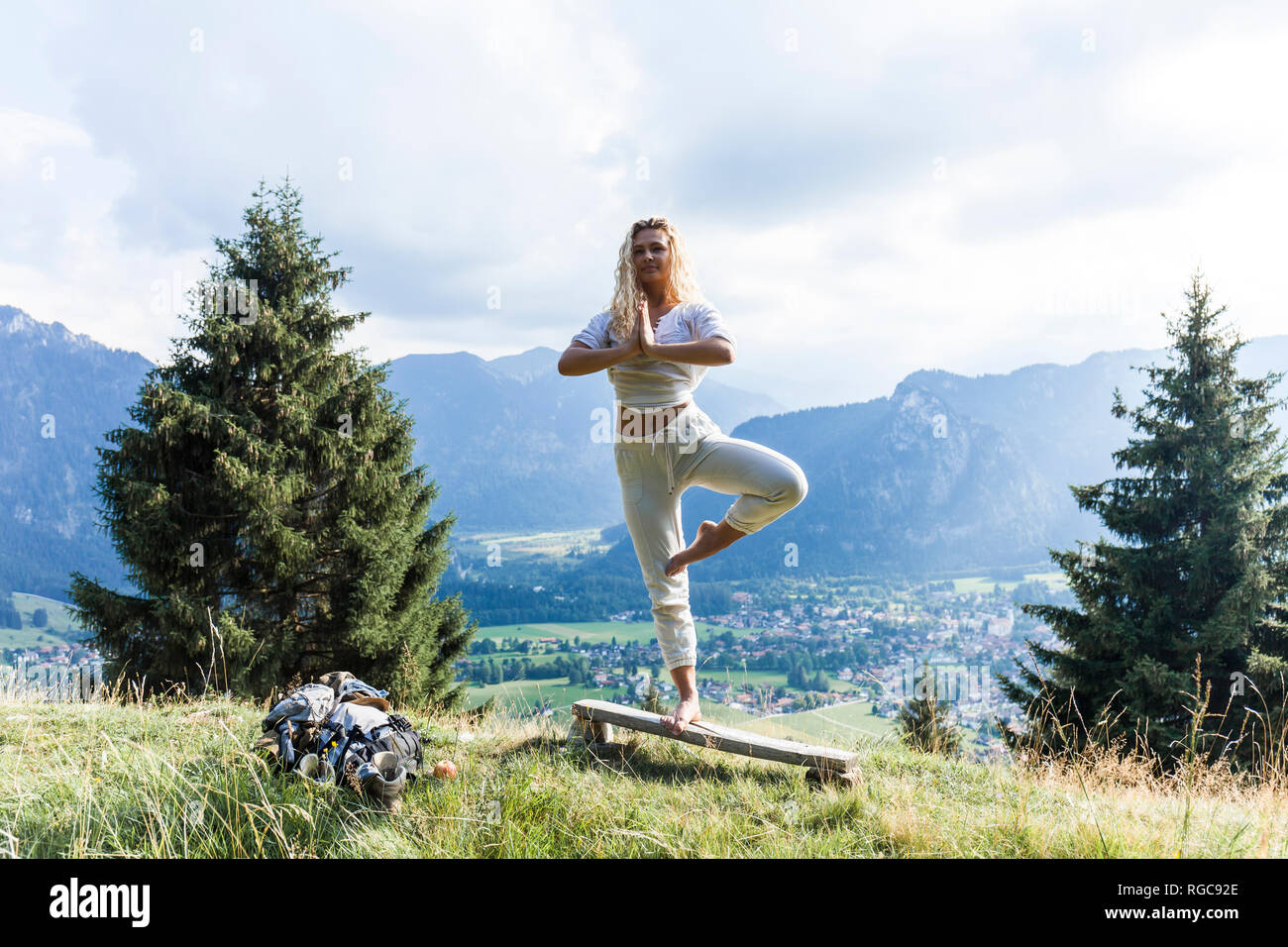 In Germania, in Baviera, Oberammergau, giovane donna fare yoga su banco sul prato di montagna Foto Stock