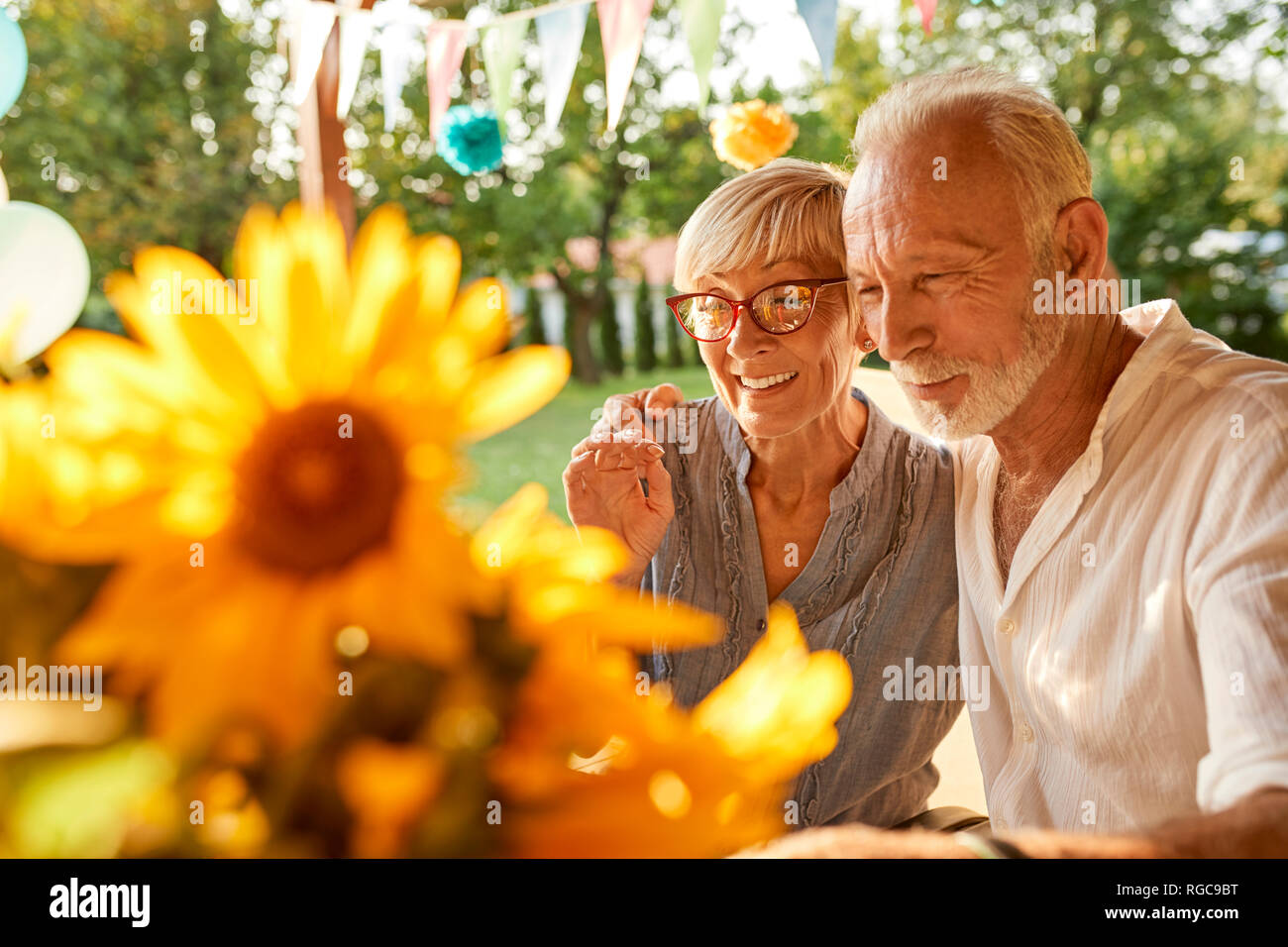 Felice coppia senior abbracciando in un party in giardino Foto Stock