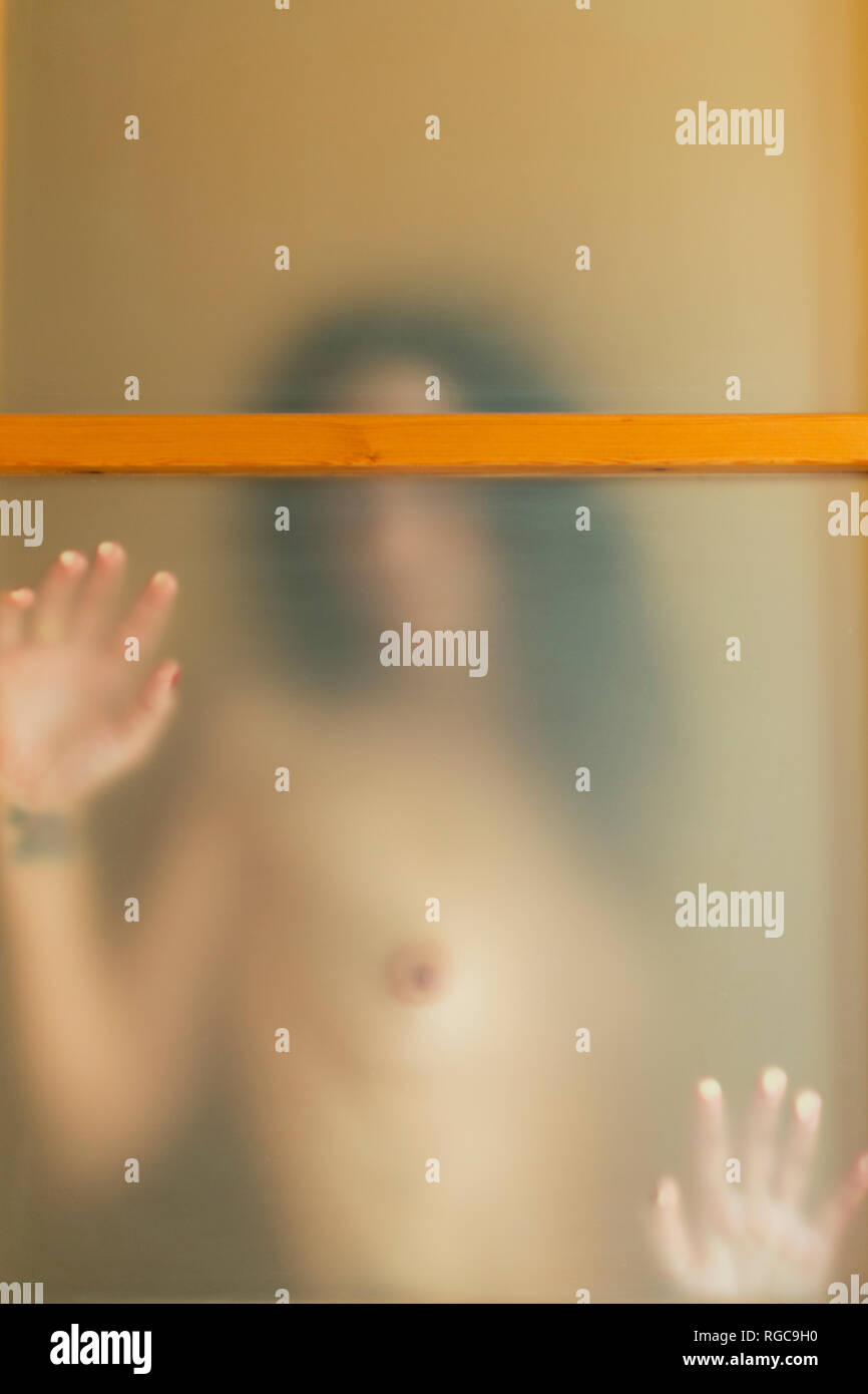 In topless di giovane donna dietro una porta traslucido Foto Stock