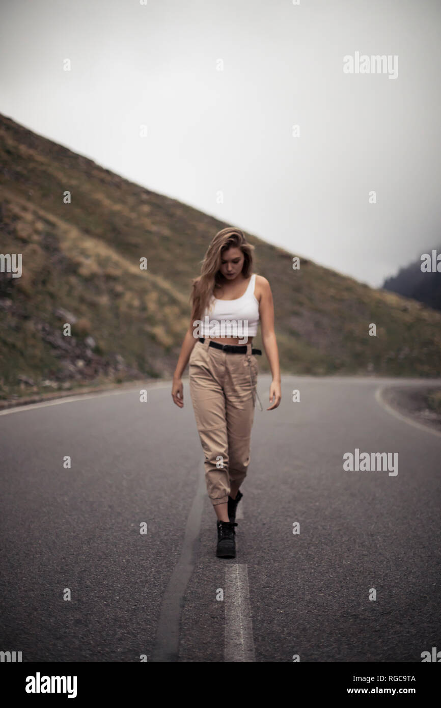 Donna bionda a camminare su una strada, persona sfocato Foto Stock