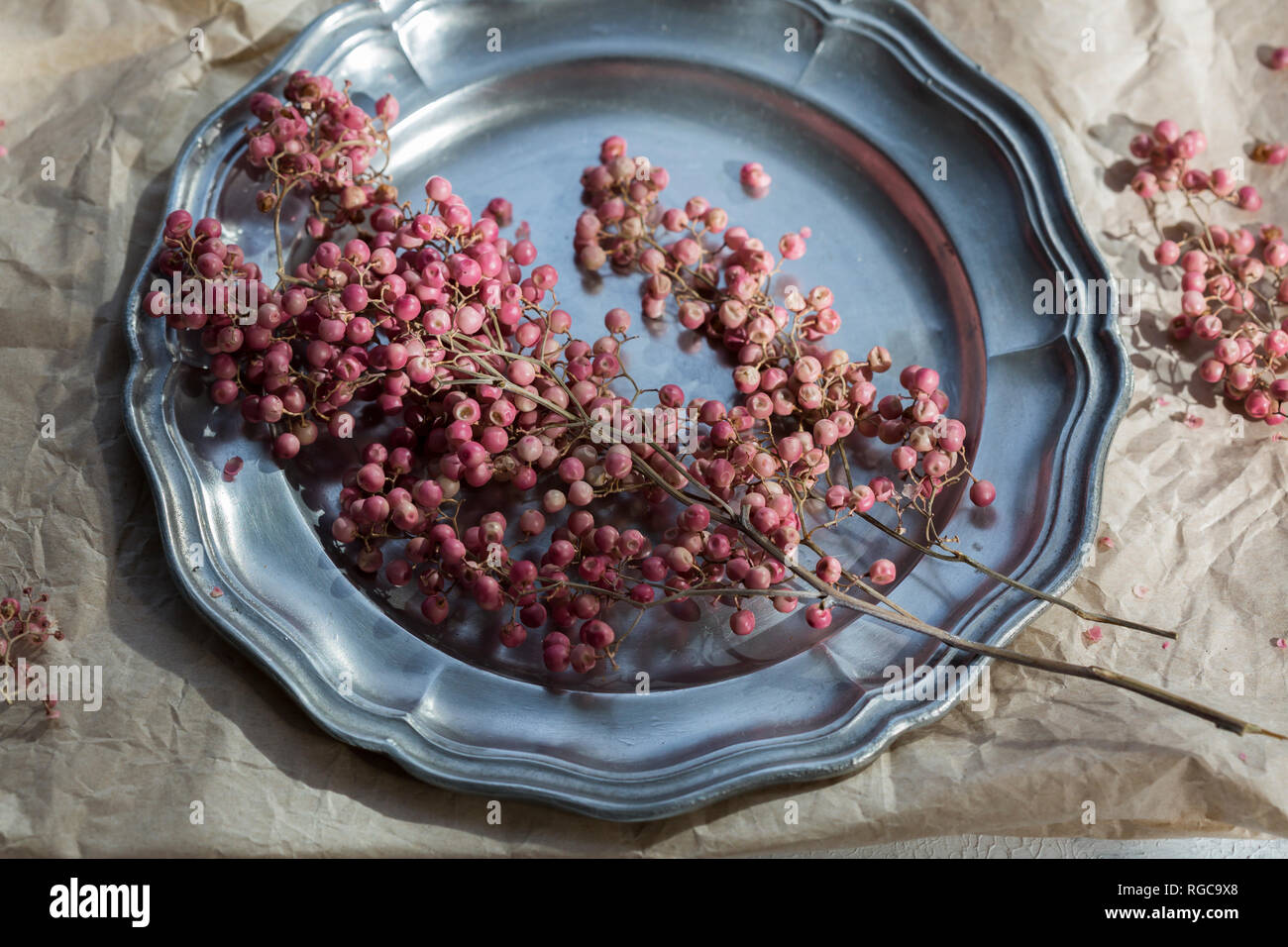 Grani di pepe rosa sulla piastra di stagno Foto Stock