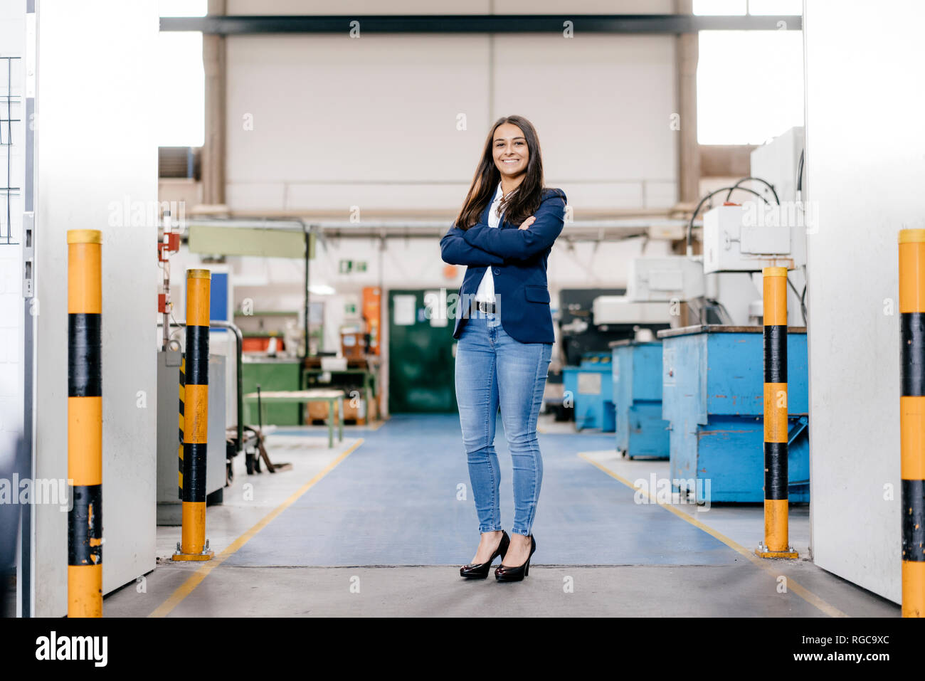 Fiducioso donna che lavorano in high tech enterprise, stando in officina in fabbrica con le braccia incrociate Foto Stock