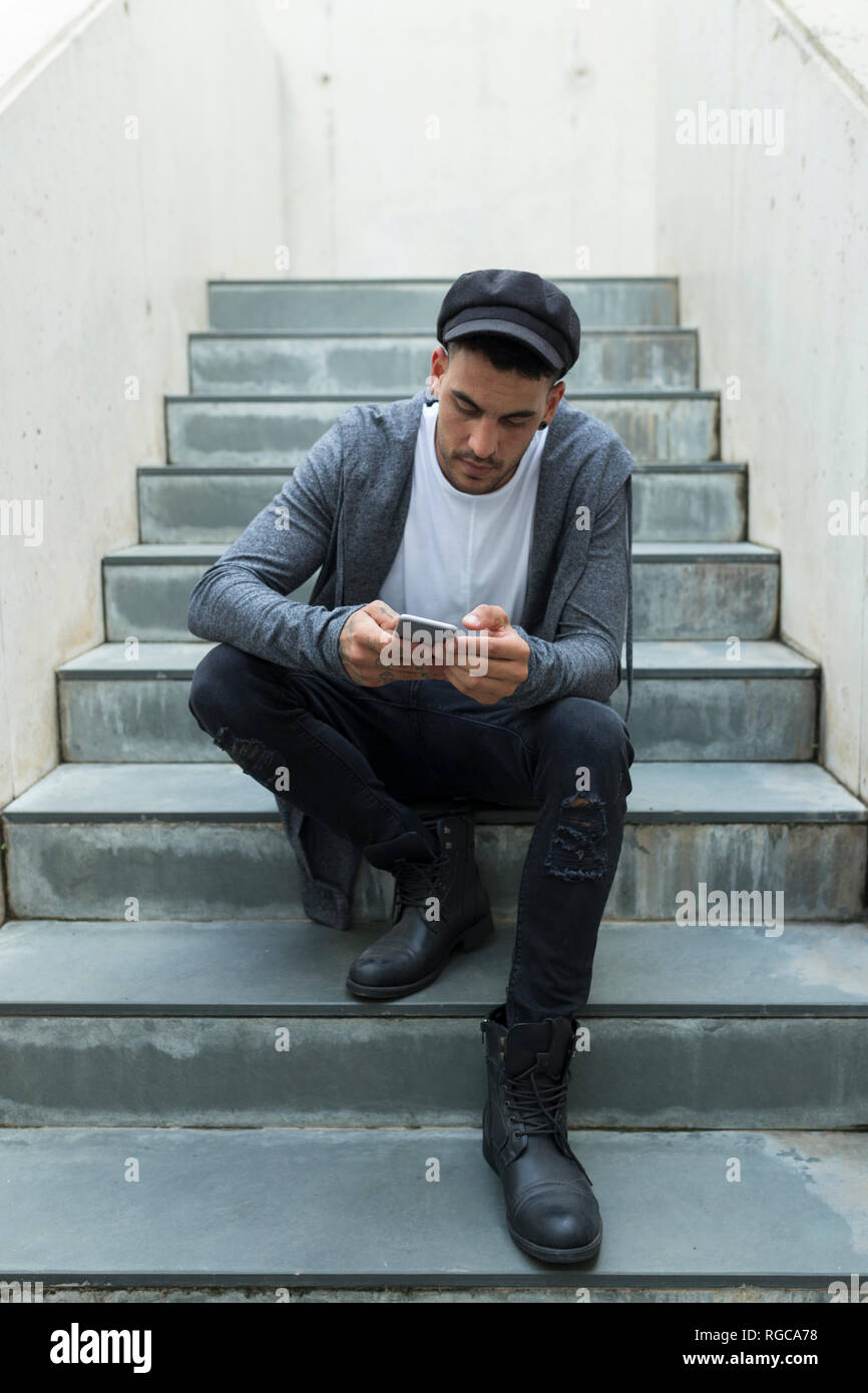 Giovane uomo seduto sulle scale utilizza lo smartphone Foto Stock