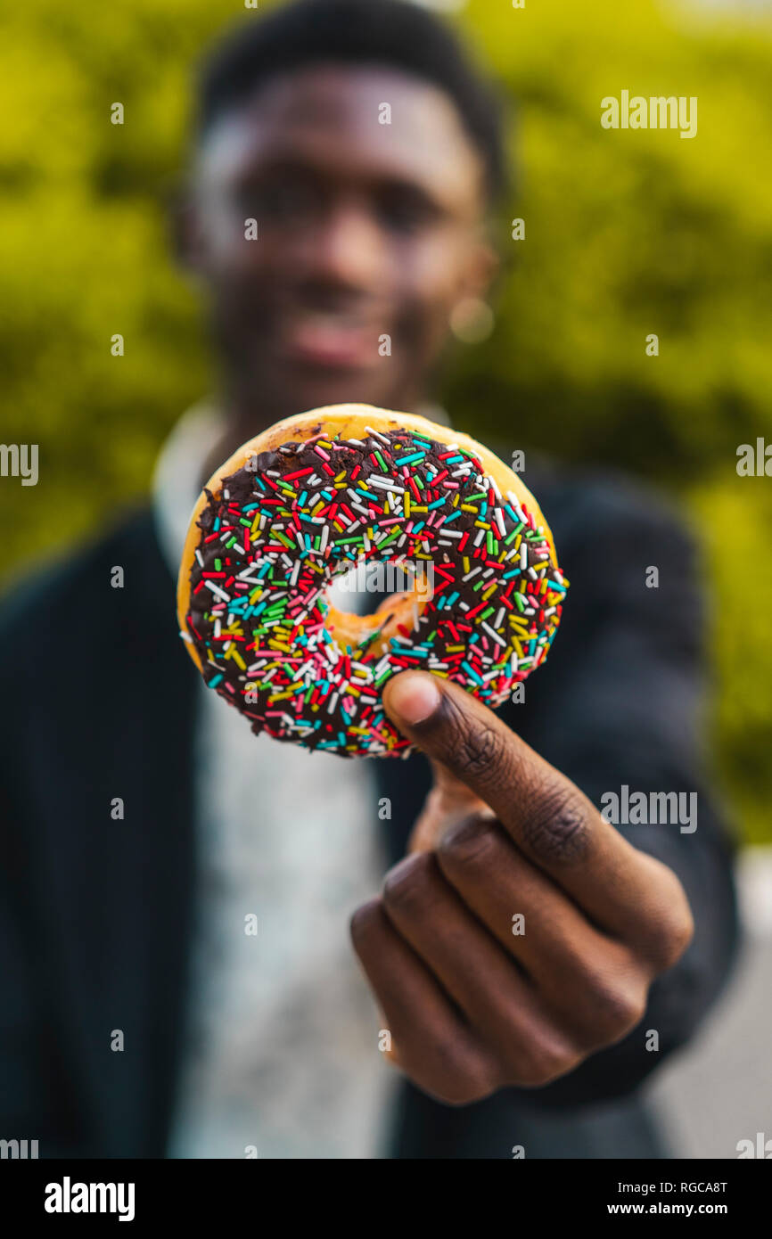 Giovane uomo nero tenendo un cookie al cioccolato Foto Stock
