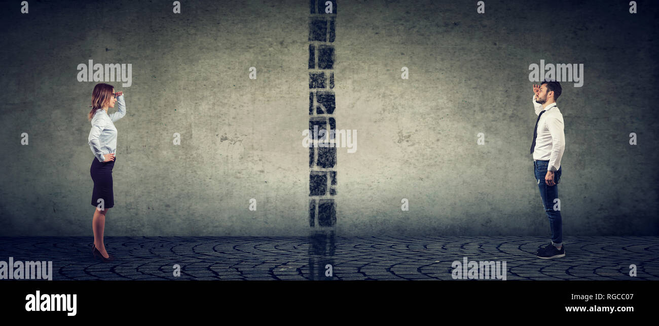 Il divario fra i sessi, le disuguaglianze e le rotture di concetto di comunicazione. Azienda giovane uomo e donna separate fra loro da una parete Foto Stock