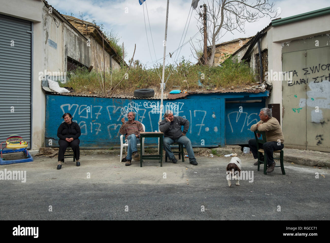 I vicini si radunano per chat nella parte anteriore di una barriera che blocca il passaggio attraverso la zona verde che divide Nicosia tra il greco e turco i lati in Foto Stock