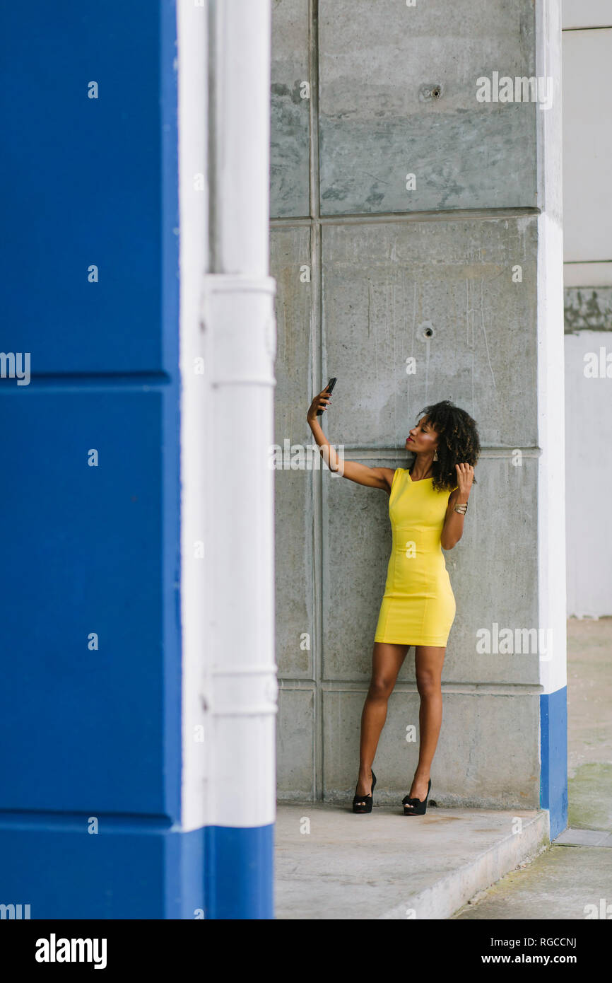 Imprenditrice di moda in abito giallo tenendo selfie con lo smartphone Foto Stock