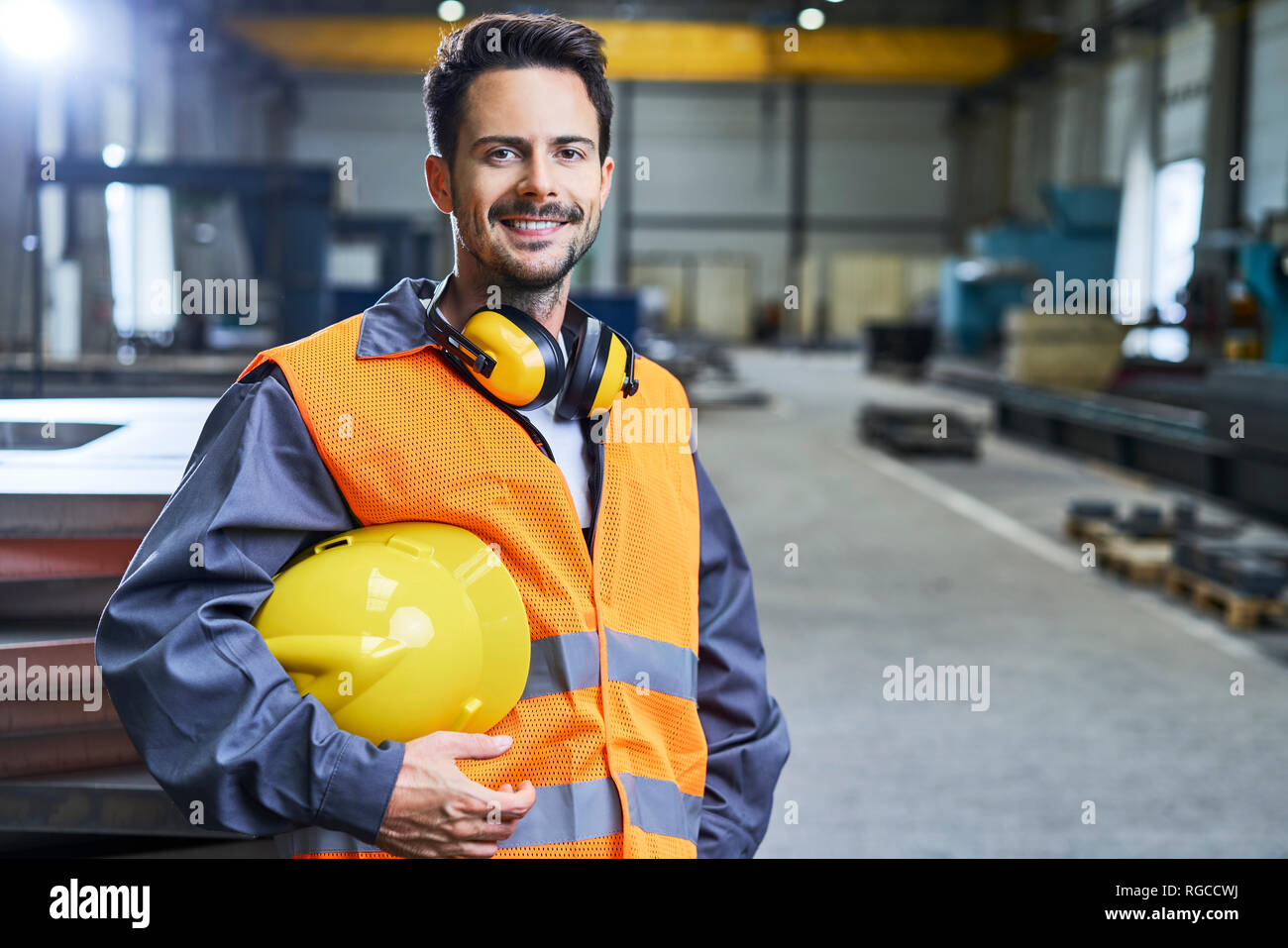 Ritratto di uomo sorridente indossando indumenti da lavoro protettiva in fabbrica Foto Stock