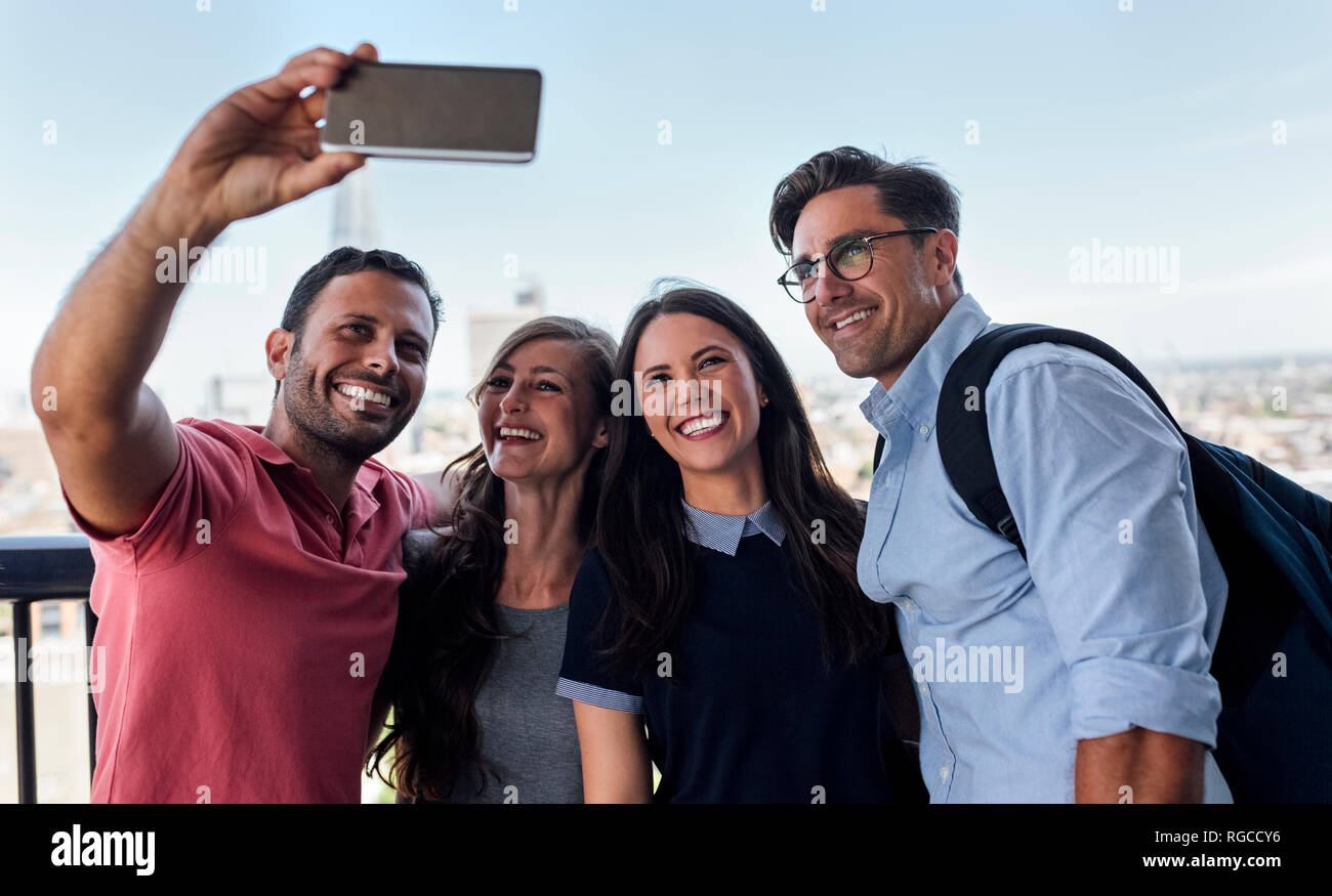 UK, Londra, quattro amici prendendo un selfie con city in background Foto Stock