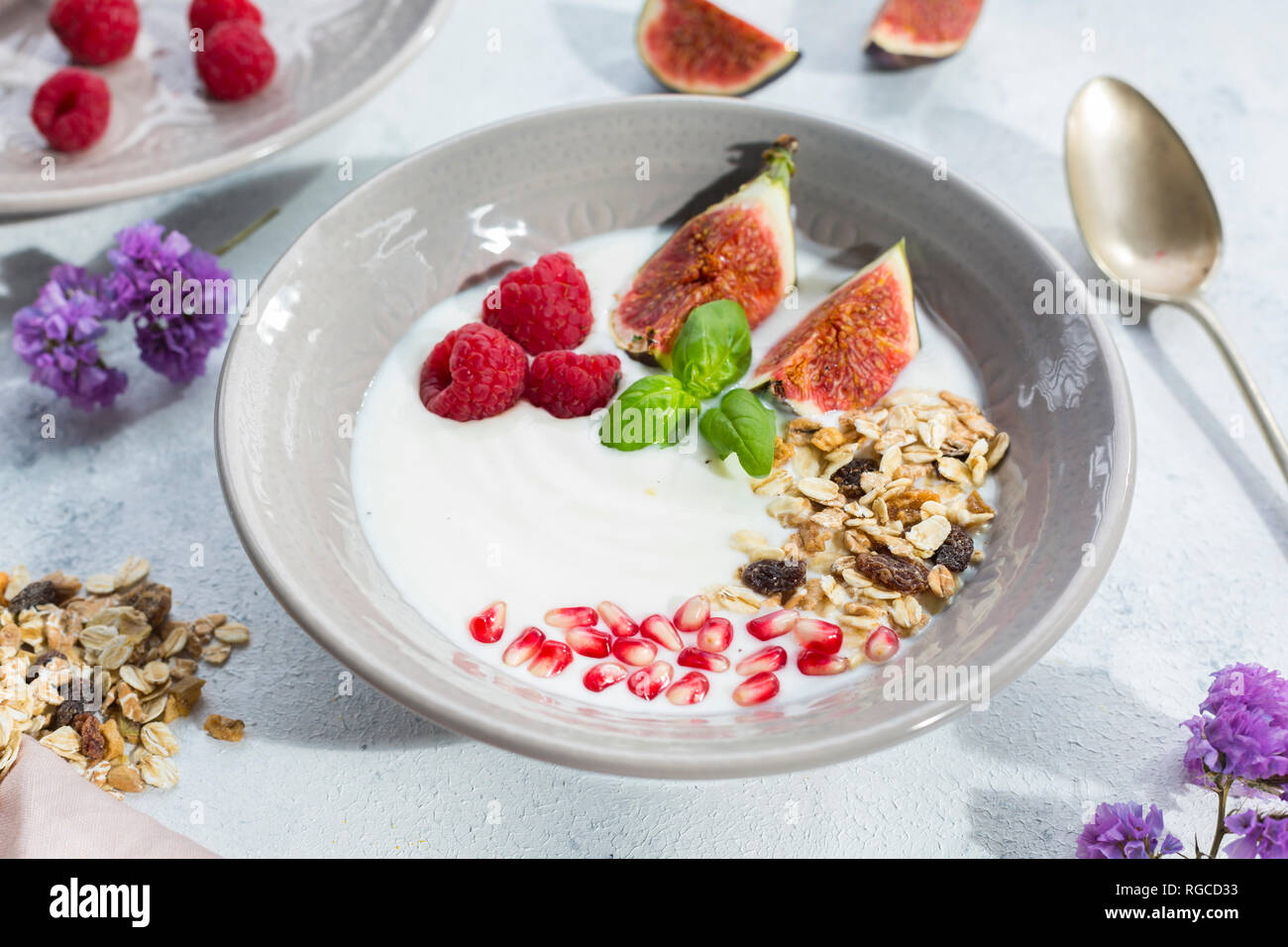 Ciotola di yogurt naturale con frutta muesli, lamponi, fichi e i semi di melograno Foto Stock