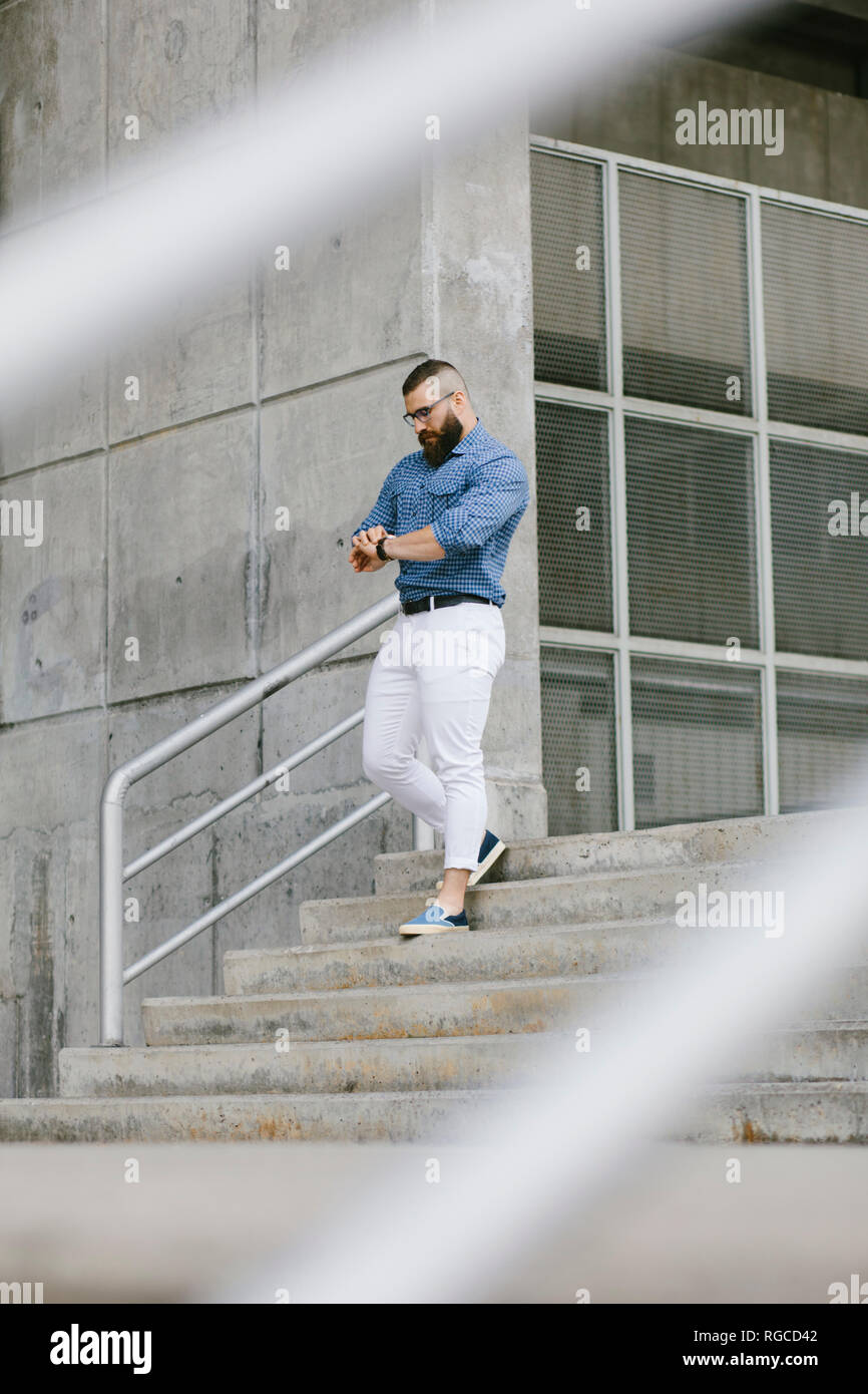 Tanga barbuto imprenditore controllando il tempo mentre si cammina al piano di sotto Foto Stock