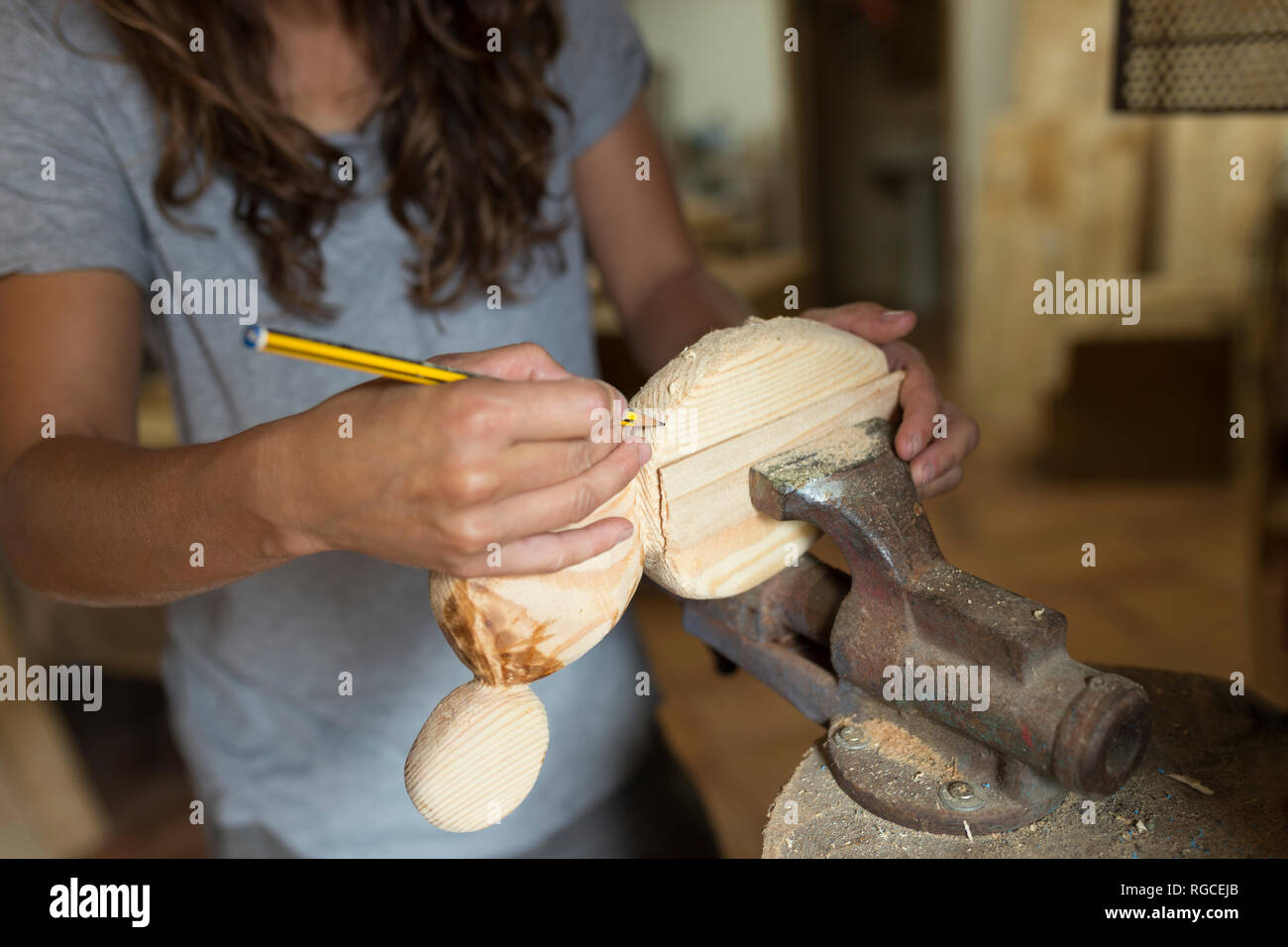 Craftswoman lavora con matita su un pezzo di legno nella sua officina Foto Stock