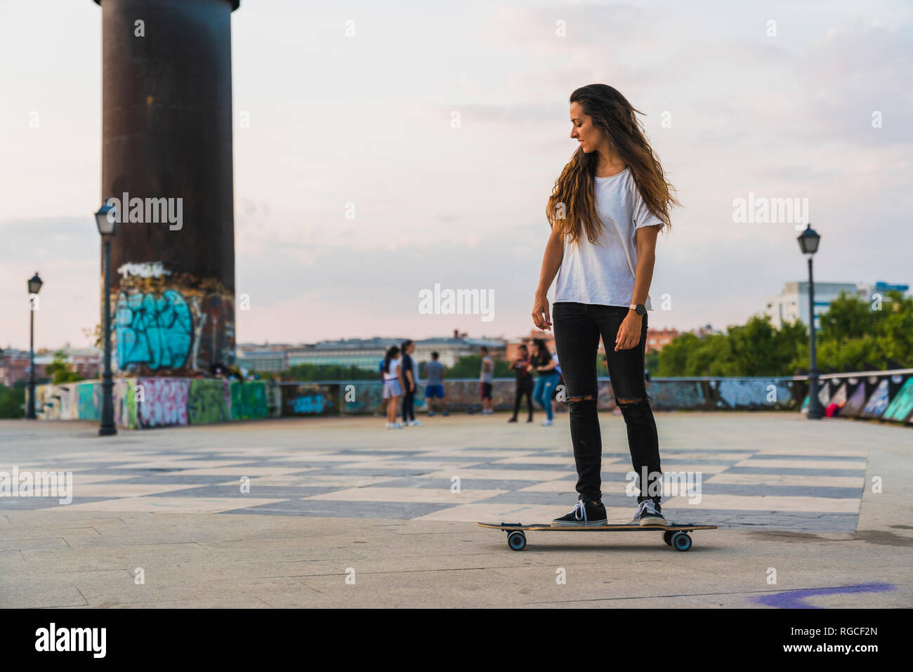 Giovane donna cavallo skateboard in città Foto Stock