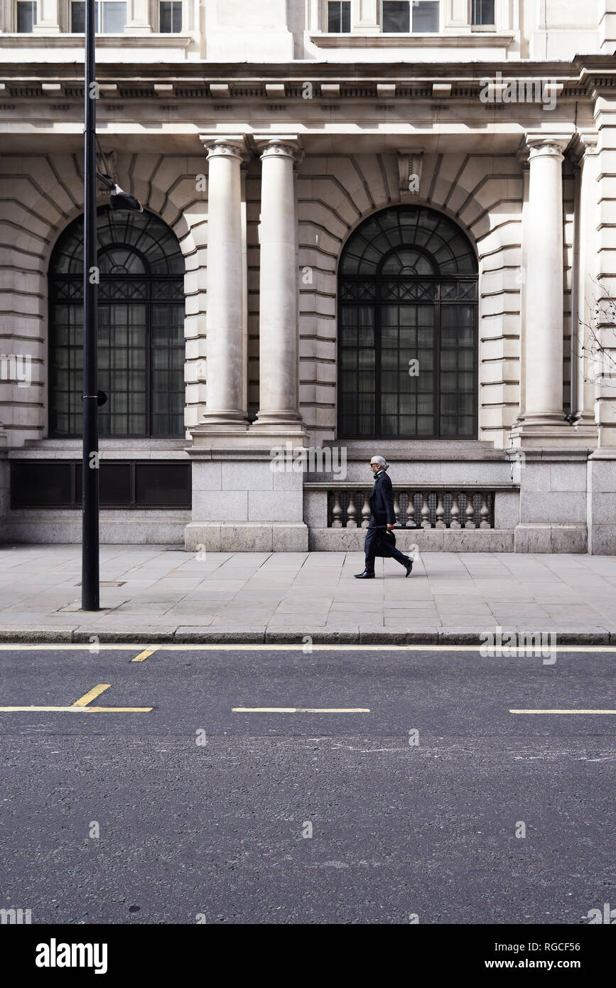 UK, Londra, senior imprenditore camminando sul marciapiede Foto Stock