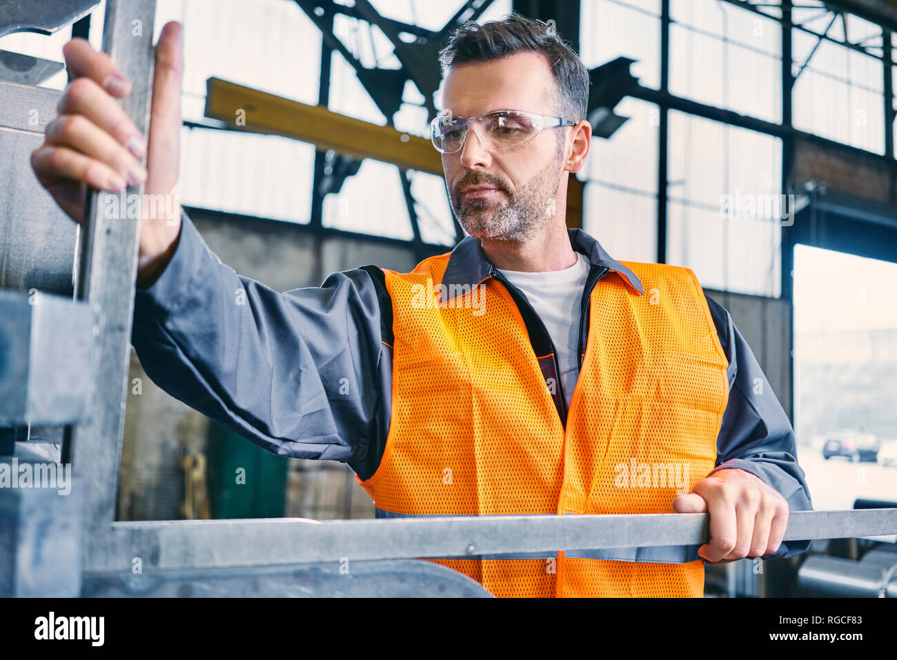 Uomo che indossa indumenti da lavoro protettiva a lavorare in fabbrica Foto Stock