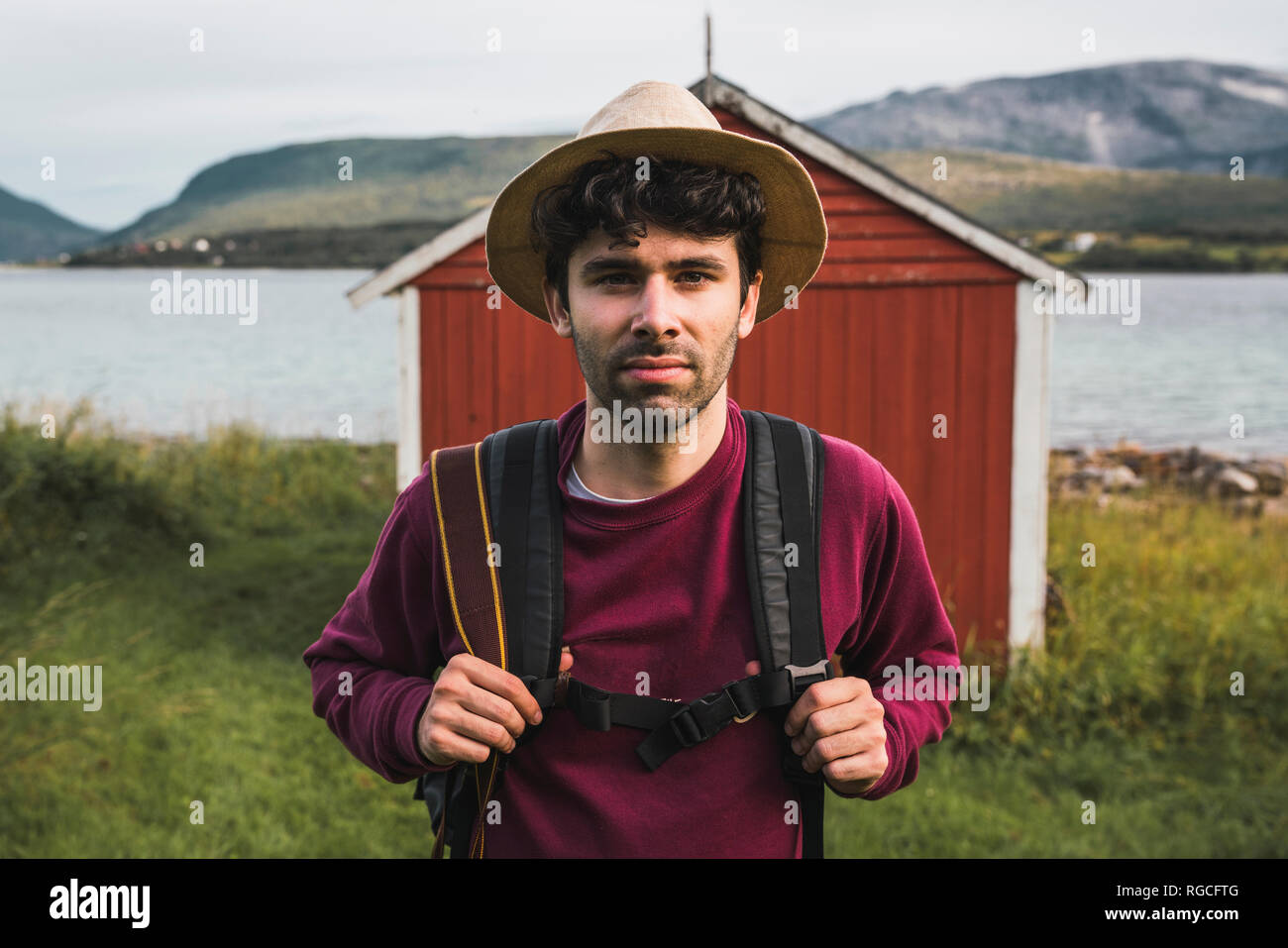Giovane uomo con zaino esplorare granaio rosso nel nord della Norvegia Foto Stock