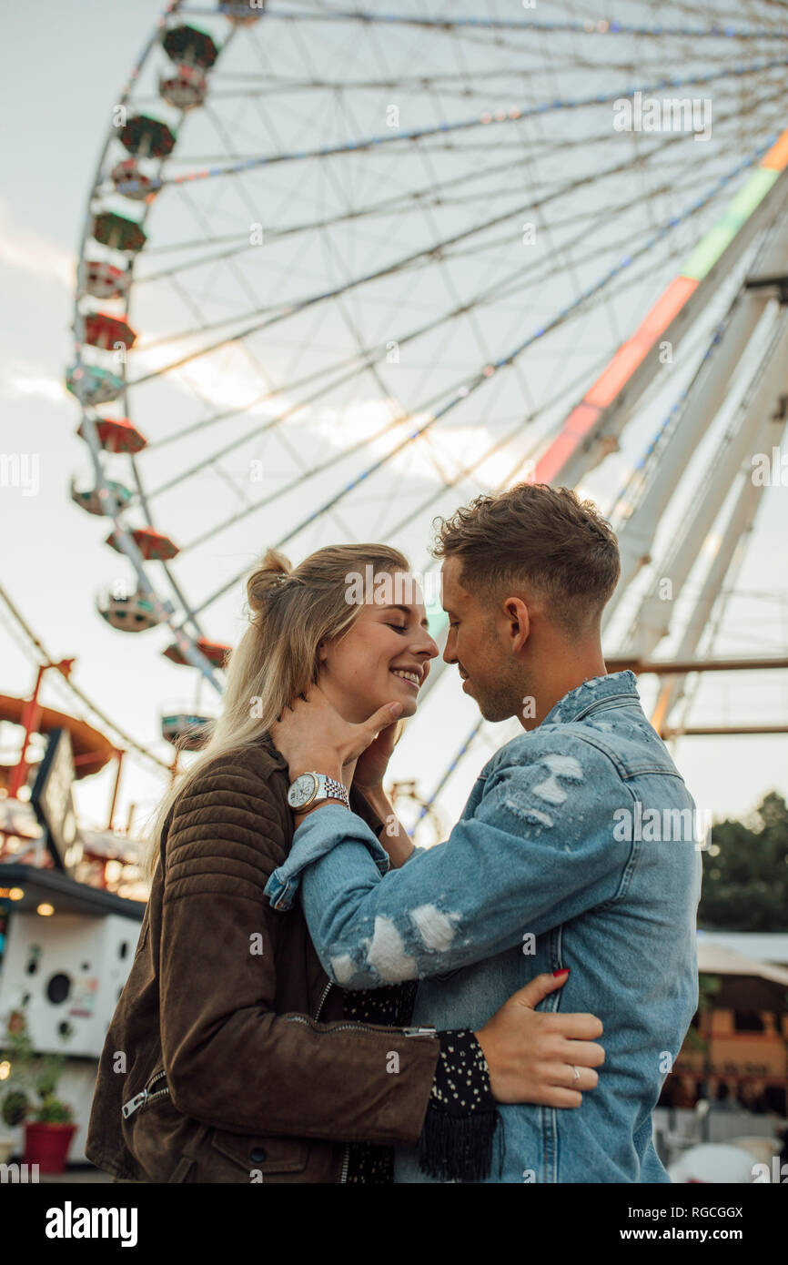 Coppia giovane in amore, baciando e abbracciando in un luna park Foto Stock