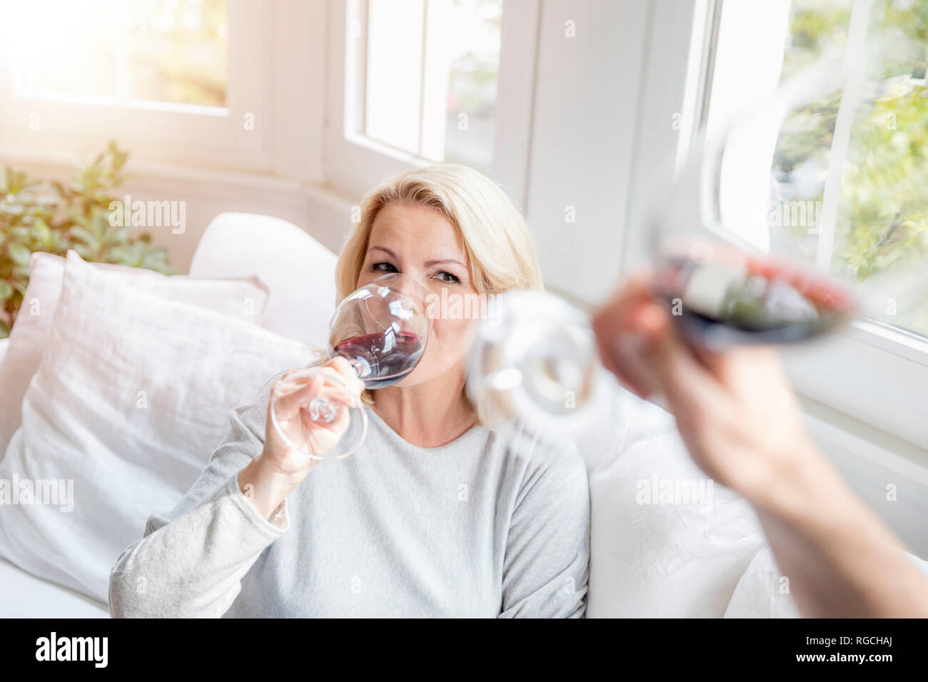 Ritratto di bionda donna matura di bere il vino rosso con il suo partner a casa Foto Stock