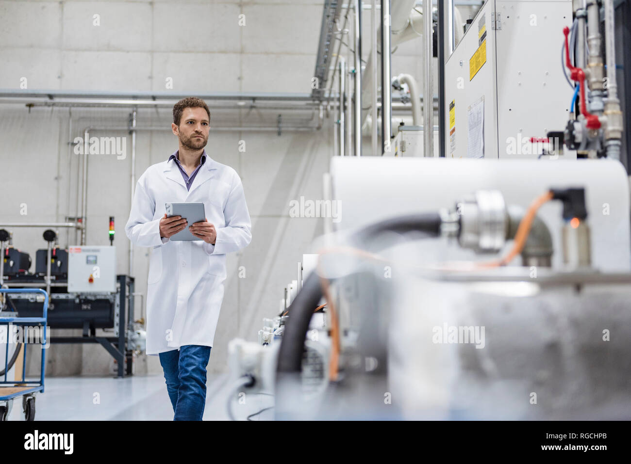 Dipendente controllare macchine operatrici in high tech company, utilizzando tavoletta digitale Foto Stock