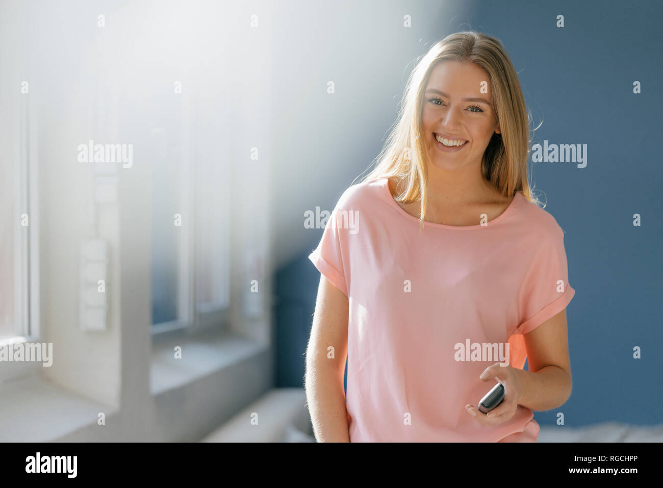 Ritratto di sorridente giovane donna con il cellulare in mano Foto Stock