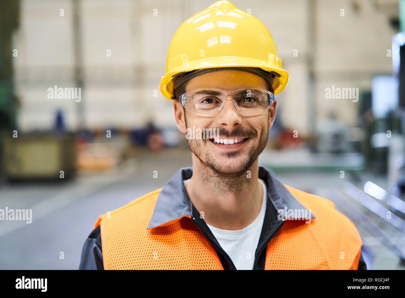 Ritratto di uomo sorridente indossando indumenti da lavoro protettiva in fabbrica Foto Stock