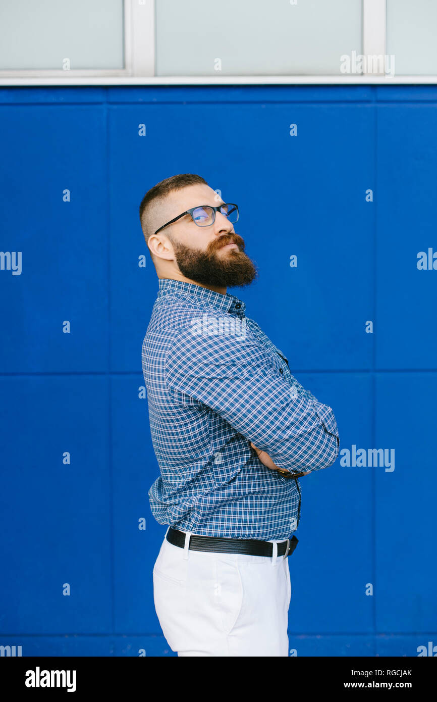 Ritratto di barbuto hipster imprenditore indossando plaid shirt in piedi di fronte a sfondo blu Foto Stock