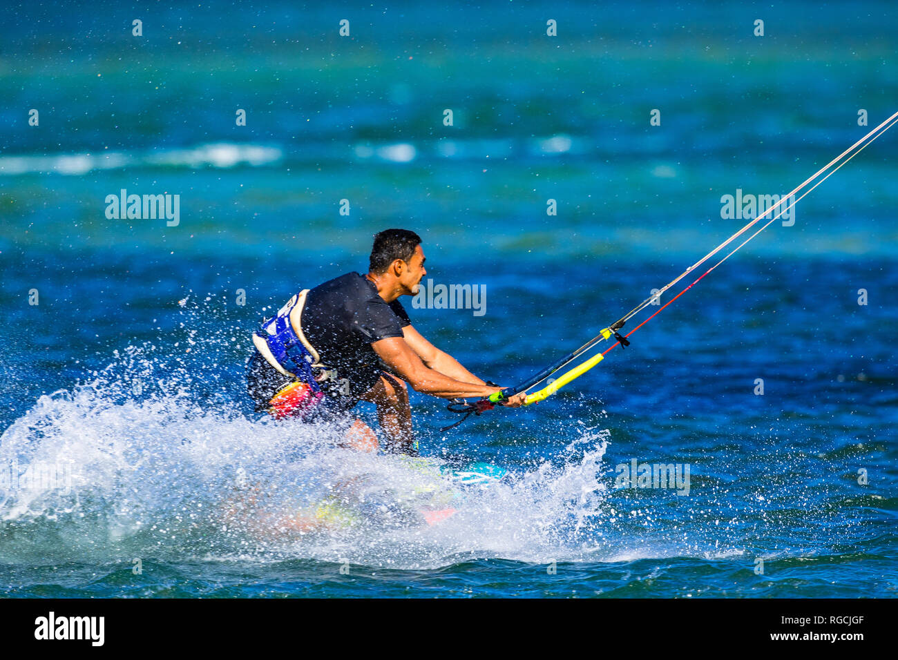 Kitesurfer sulla Costa del Sole tira fuori alcune mosse acrobatiche sulle acque blu turchese nel Queensland, Australia Foto Stock