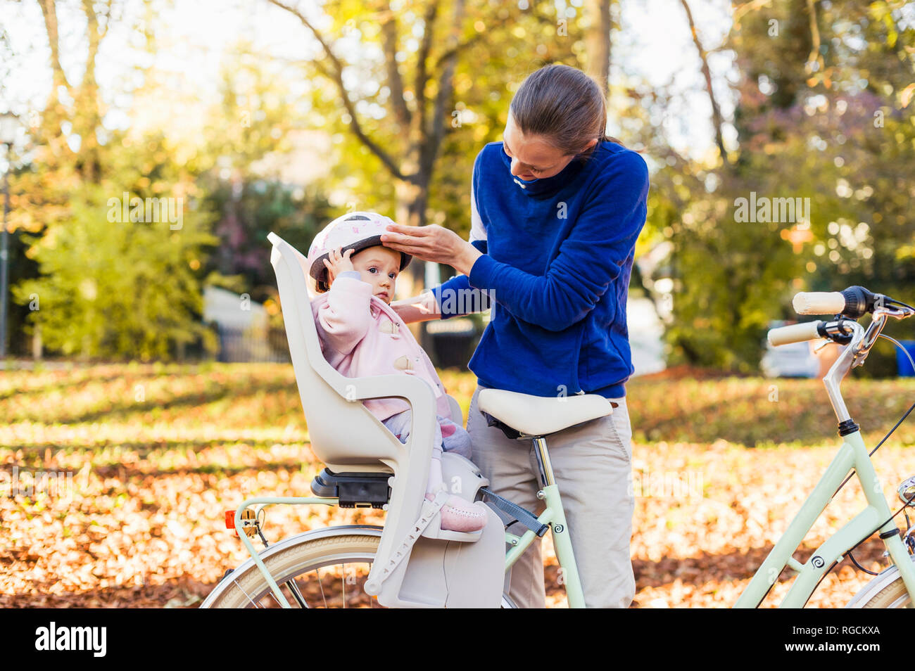 Madre e figlia Bicicletta Equitazione, baby indossando il casco in seduta i bambini del posto di guida Foto Stock