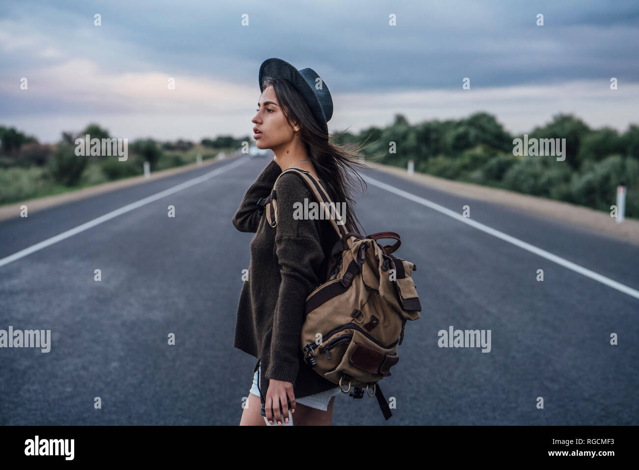 Ritratto di autostop giovane donna con zaino e bevanda sul lane Foto Stock