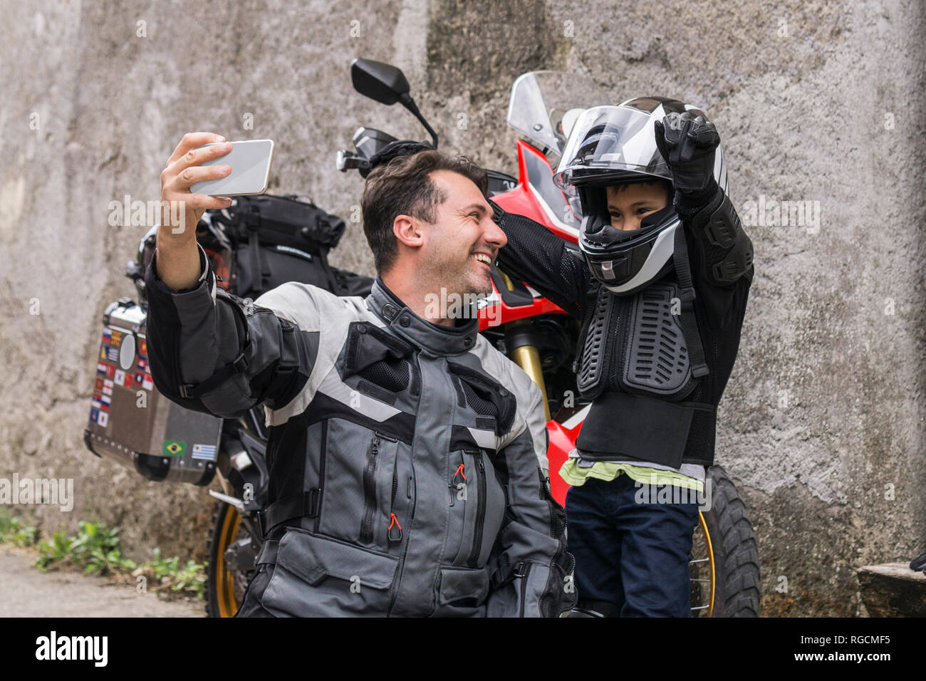 Felice padre e figlio prendendo un selfie su un viaggio in moto Foto Stock