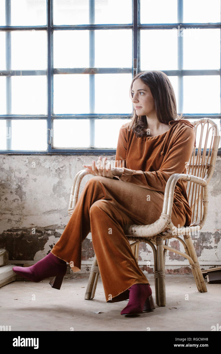 Moda giovane donna seduta sul cestello una sedia a sdraio in un loft Foto Stock