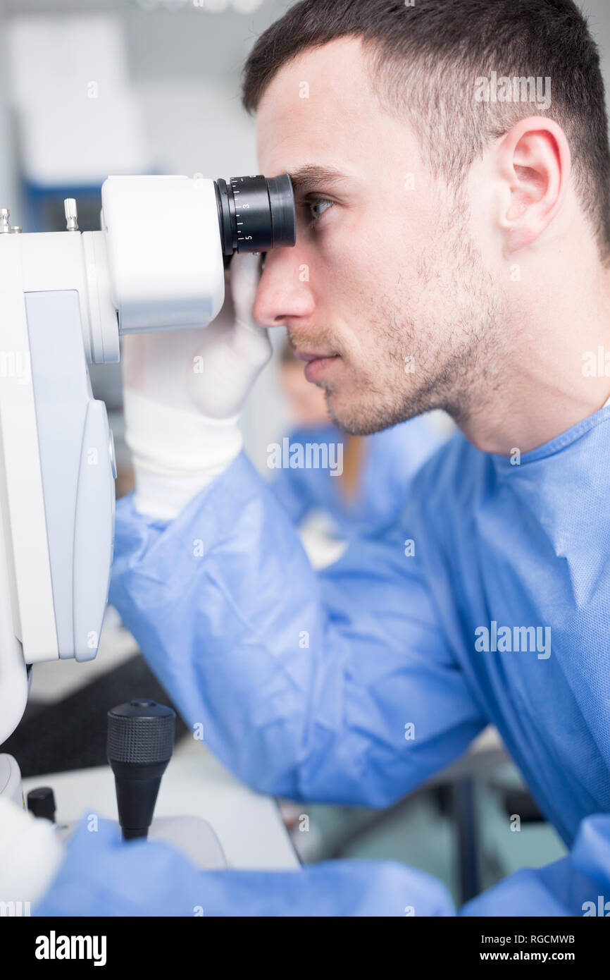 Tecnico di laboratorio guardando attraverso il microscopio Foto Stock