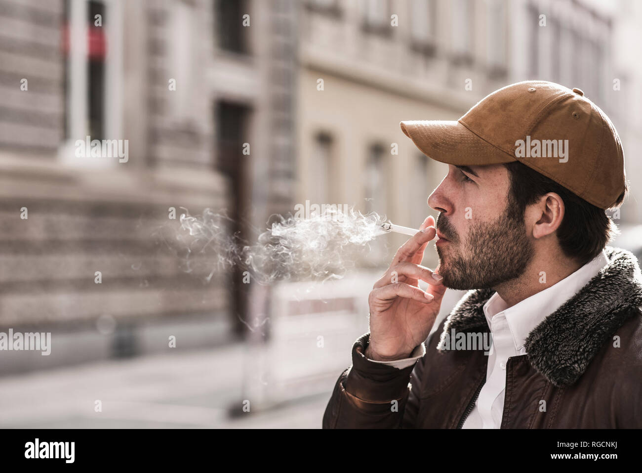 Ritratto di giovane uomo con berretto da baseball Sigaretta fumare Foto Stock