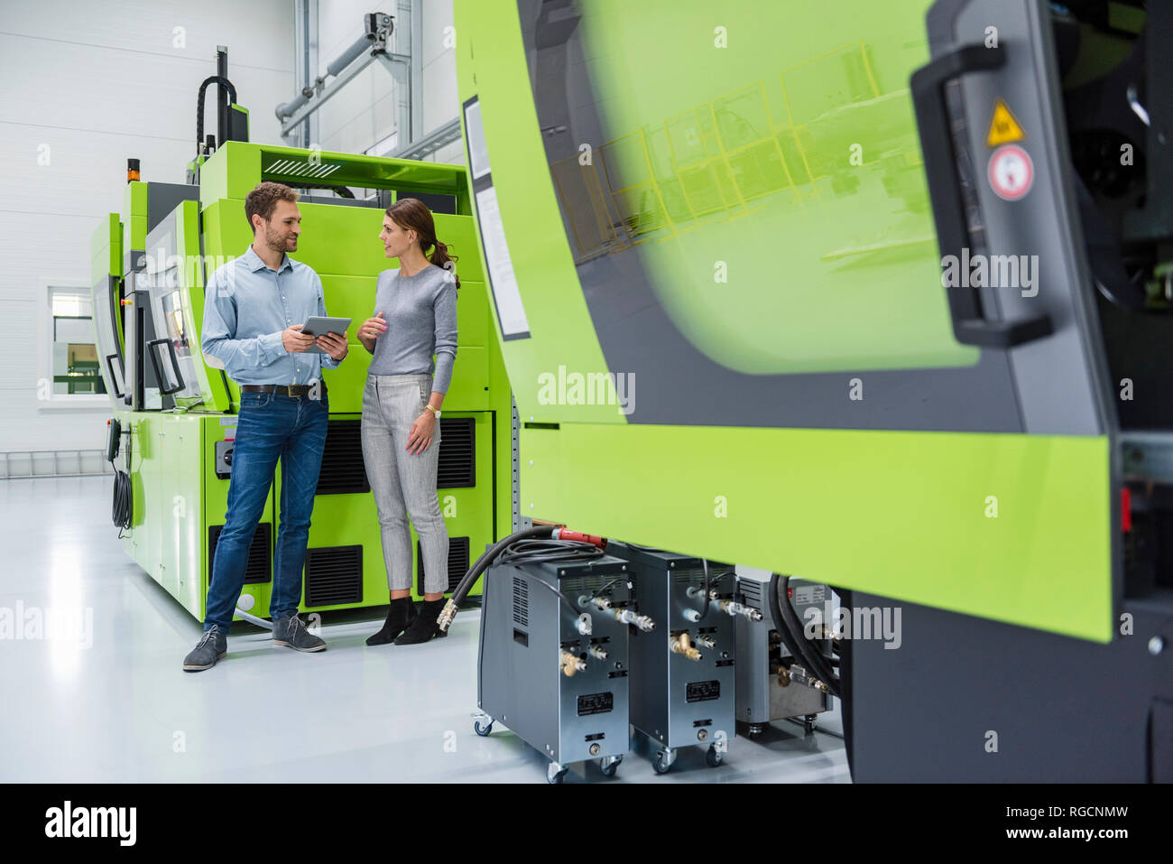 I colleghi di high tech impresa in grado di controllare le macchine di fabbricazione, utilizzando tavoletta digitale Foto Stock