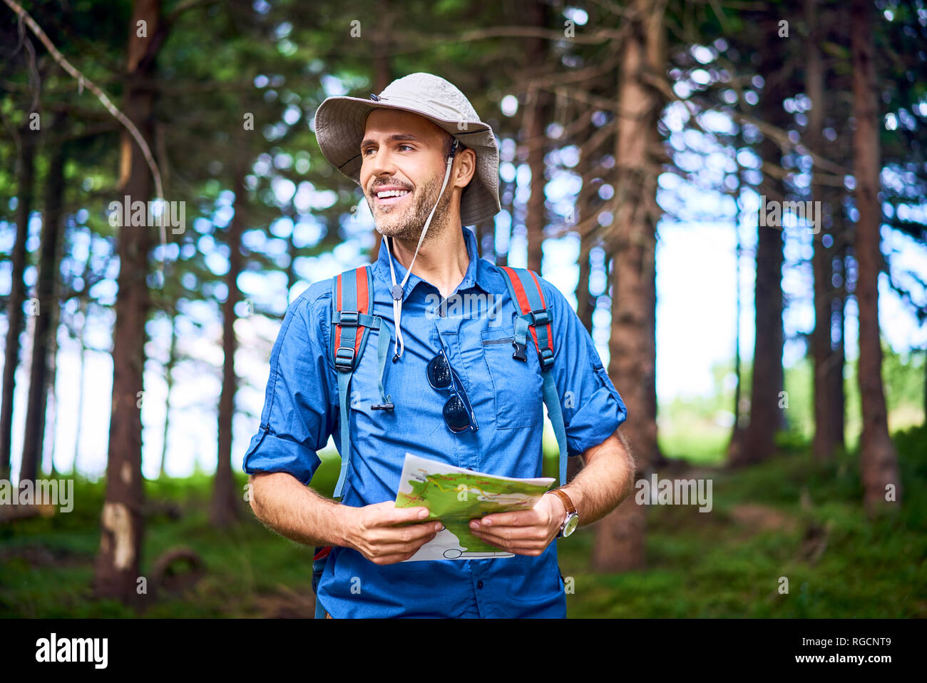 Uomo sorridente in possesso di una mappa escursioni nella foresta Foto Stock