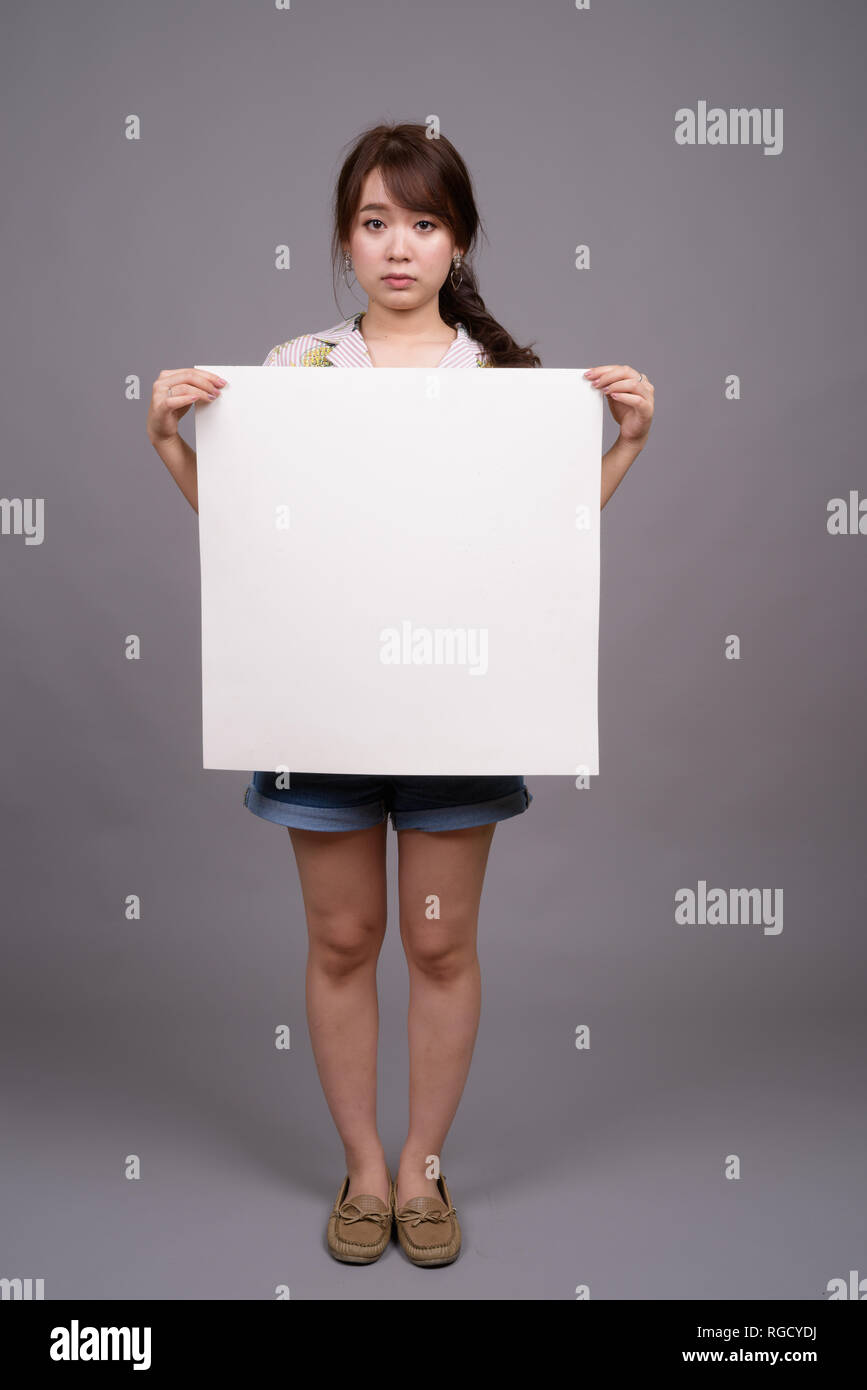 Donna asiatica holding vuoto lavagna bianca con copyspace Foto Stock