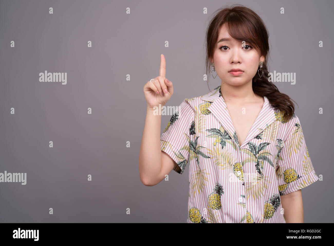Asian tourist donna puntare il dito e mostrando copyspace Foto Stock