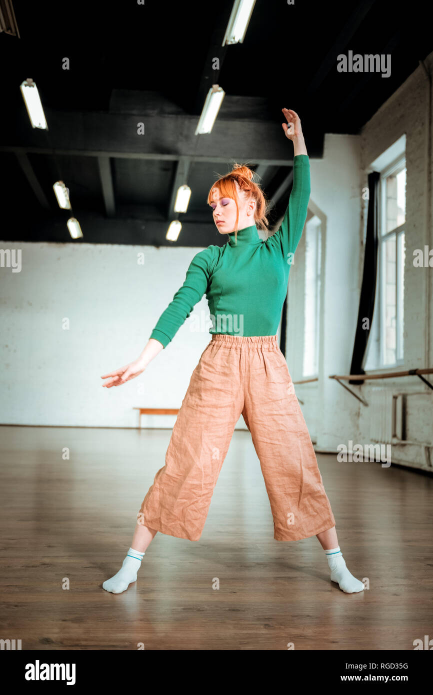 Piacevole guardando montare istruttore yoga in un verde turtleneck cercando concentrata Foto Stock