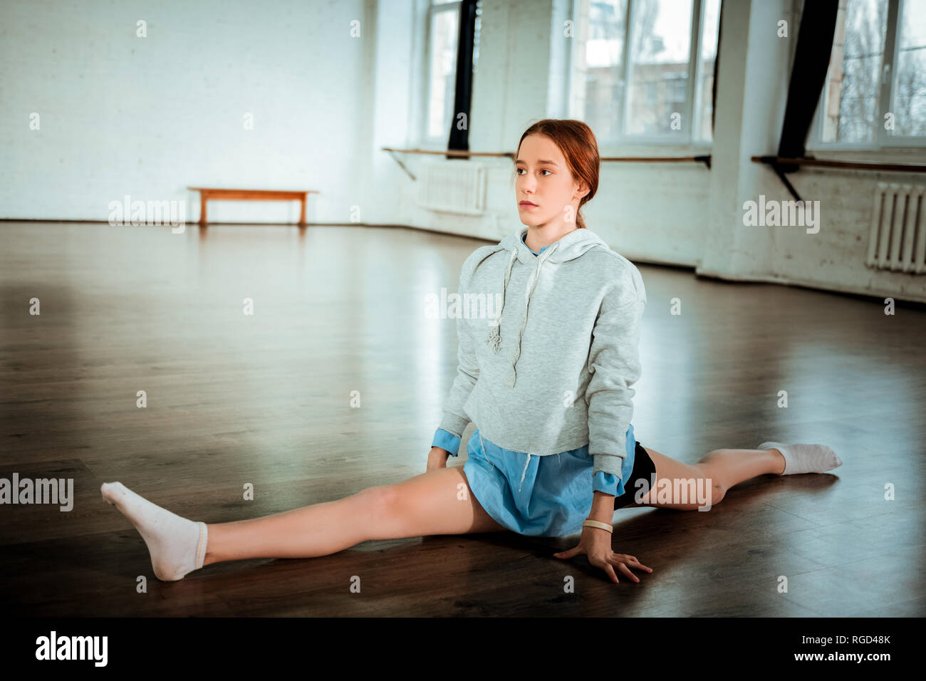 Piuttosto scuro con capelli adolescente in pantaloncini nero facendo gambe-split Foto Stock