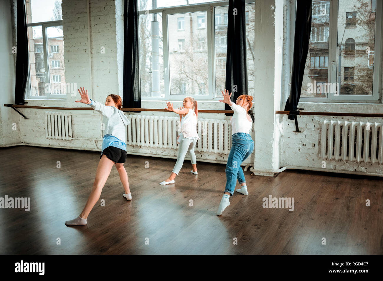 I capelli rossi insegnante di danza in jeans blu e i suoi studenti che esercitano in studio Foto Stock