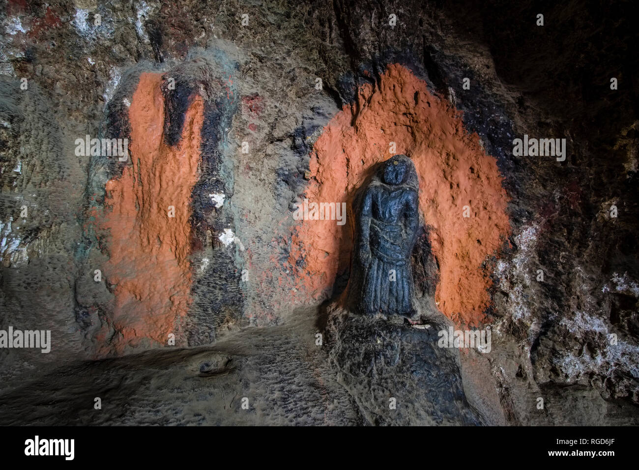 Statua di colore nero all'interno Chungsi grotta, situata nel paesaggio alpino con ripide pareti rocciose e profonde valli in Mustang Superiore Foto Stock