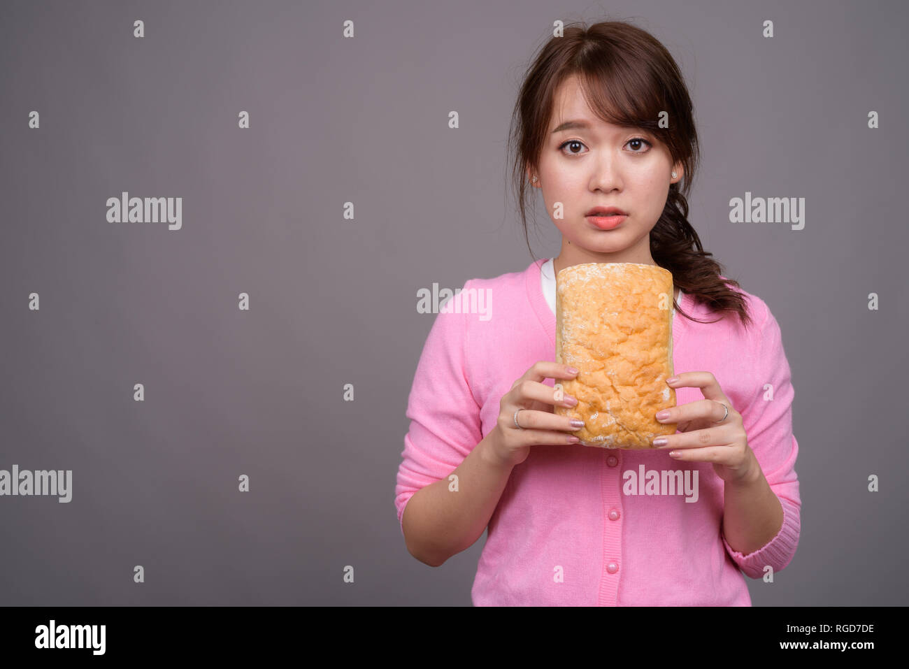 Giovane bella donna asiatica holding pezzo di pane Foto Stock